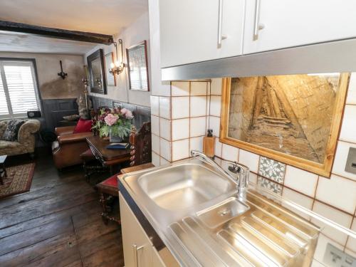 a kitchen with a sink and a living room at The Old Paper Shop in Tewkesbury
