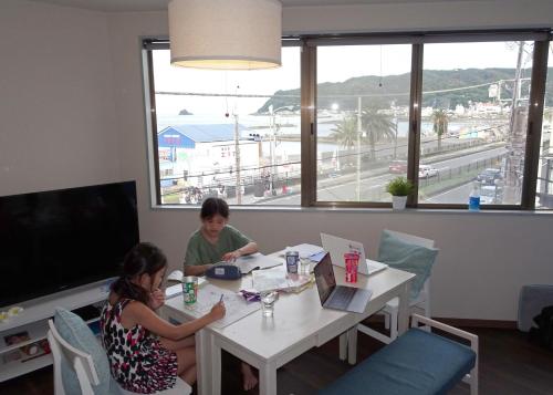 two people sitting at a table with their laptops at Izu no ie MOANA in Ito