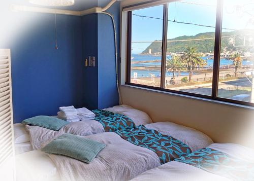 three beds in a room with a view of a beach at Izu no ie MOANA in Ito