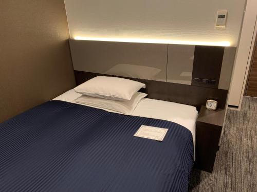 um pequeno quarto com uma cama com uma almofada branca em Ochanomizu Inn em Tóquio