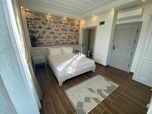 a bedroom with a white bed and a brick wall at Cunda Ömer Ağa Konağı in Cunda
