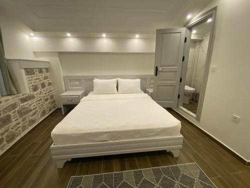 a bedroom with a white bed and a mirror at Cunda Ömer Ağa Konağı in Cunda
