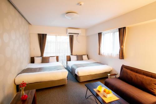 a hotel room with two beds and a couch at BON Kyoto Station in Kyoto