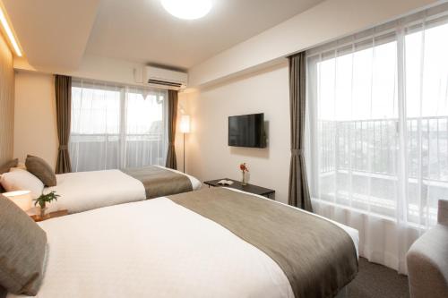 a hotel room with two beds and a window at BON Kyoto Station in Kyoto