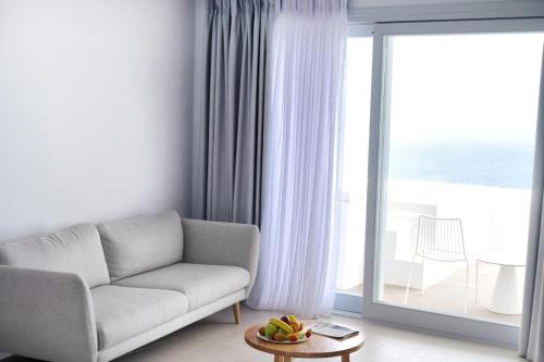 a living room with a couch and a large window at Lilium Hotel Santorini in Fira