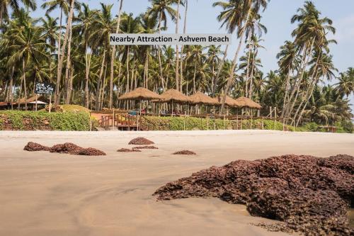 a beach with some rocks in the sand and palm trees at Oceans 7 Ashwem in Mandrem