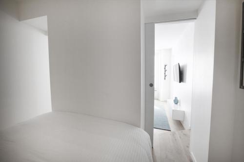 Dormitorio blanco con cama y pasillo en Stylist and cosy appartement in Montparnasse, en París