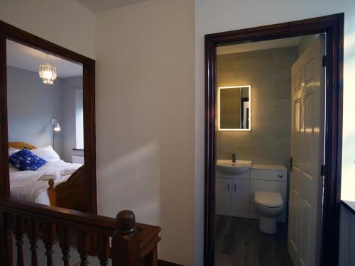 a bedroom with a bed and a sink and a mirror at Bela Cottage in Milnthorpe