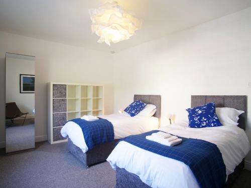 a bedroom with two beds and a chandelier at Bela Cottage in Milnthorpe