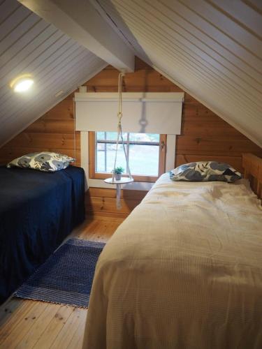 a attic bedroom with two beds and a window at Villa Taikuri in Kyläniemi