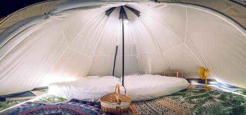 桃園區的住宿－晃晃印地安帳棚露營區，配有床和遮阳伞的白色帐篷