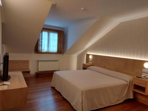 1 dormitorio con 1 cama y TV. en Hotel - Restaurante Casa Rosita, en Cambados