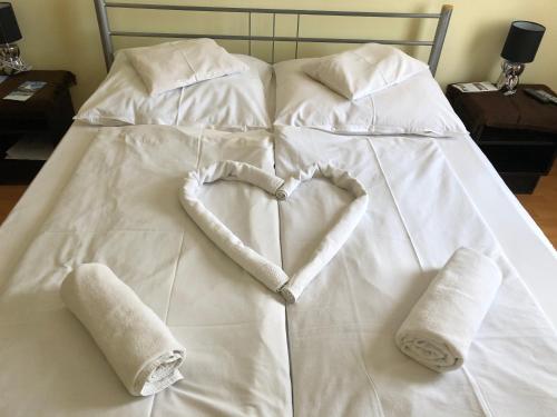 a white bed with towels in the shape of a heart at Hotel Oroszlán Szigetvár in Szigetvár