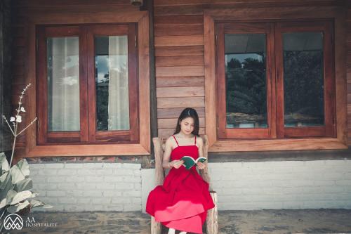 a woman in a red dress sitting in front of a building at The Nordic Village - Evergreen Retreat in Mộc Châu