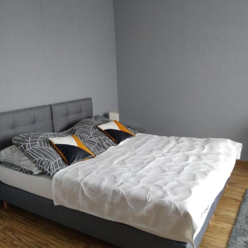 a bed with white sheets and pillows in a bedroom at Centrum - Mala Apartamenty in Wejherowo