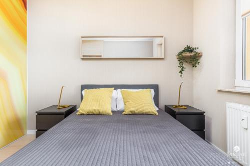 コウォブジェクにあるJantar Apartamenty - Miodowy Dom City Centerのベッドルーム1室(黄色い枕2つ付きのベッド1台付)