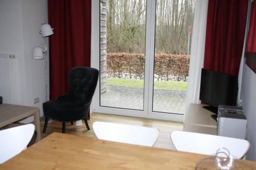 ein Wohnzimmer mit einem Tisch, einem Stuhl und einem Fenster in der Unterkunft SeeLodge Jabel Appartment 2 in Jabel