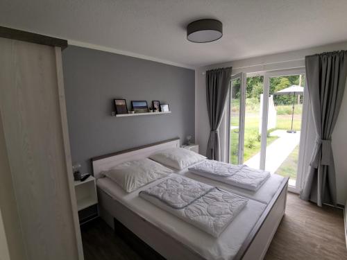 Schlafzimmer mit einem Bett mit weißer Bettwäsche und einem Fenster in der Unterkunft Ferienwohnung EG Graal-Müritz im Küstenwald in Graal-Müritz