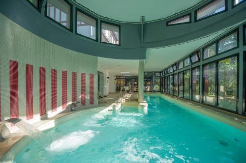 a large swimming pool in a building with windows at Hôtel Miléade Les Pléïades La Baule in La Baule