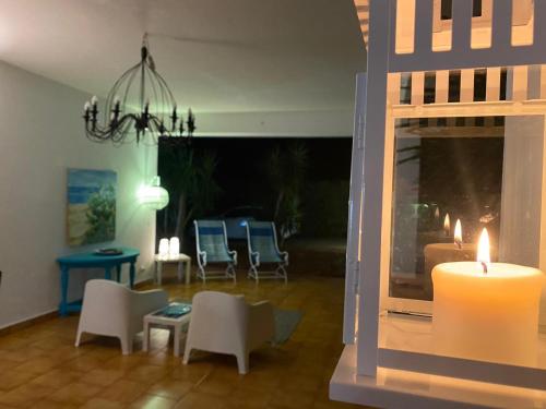 sala de estar con velas y sillas en Villa Messi, en Castelluzzo