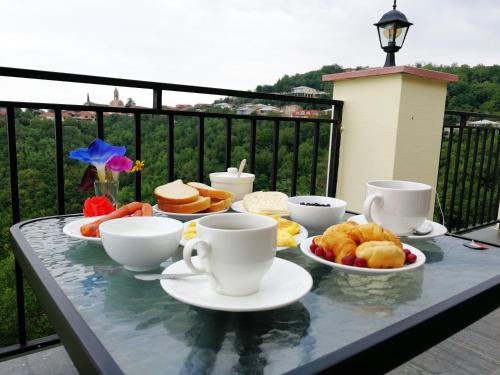 una mesa con tazas y platos de comida en el balcón en Favourite, en Signagi
