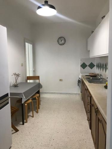 a kitchen with a table and a clock on the wall at résidence les oliviers in Soliman