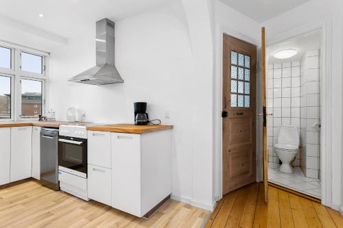 a white kitchen with a sink and a toilet at aday - Apartment suite Aalborg Center in Aalborg