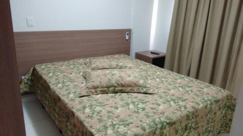 a bedroom with a bed with a bedspread with flowers at Veredas Rio Quente 110 in Rio Quente