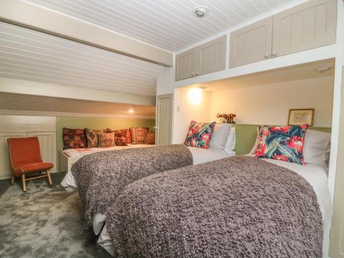 1 dormitorio con 2 camas y silla roja en The Stone Masons House, en Keighley