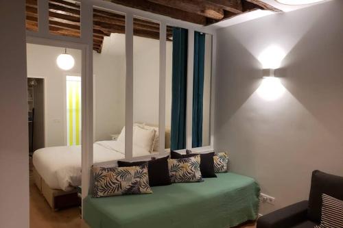 - une chambre avec un lit et un canapé avec des oreillers dans l'établissement CHARMING Saint GERMAIN ODEON LUXEMBOURG, à Paris