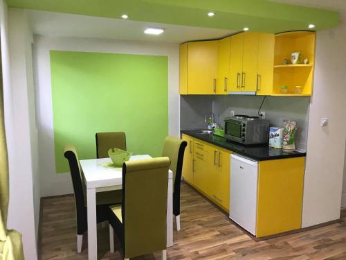 a kitchen with yellow cabinets and a table with chairs at Studio Ivana 2 in Soko Banja