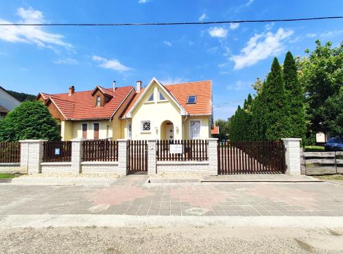 a white house with a fence and a gate at Apollo Vendégház in Bogács