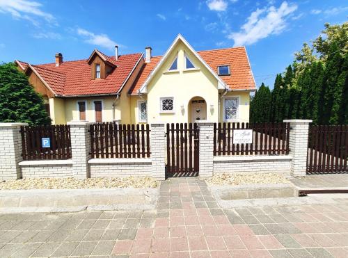 una casa con una valla y un techo rojo en Apollo Vendégház, en Bogács