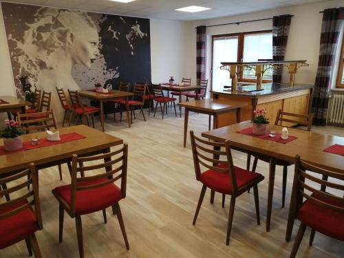 Pension Brandner في Altrandsberg: مطعم بطاولات خشبية وكراسي حمراء