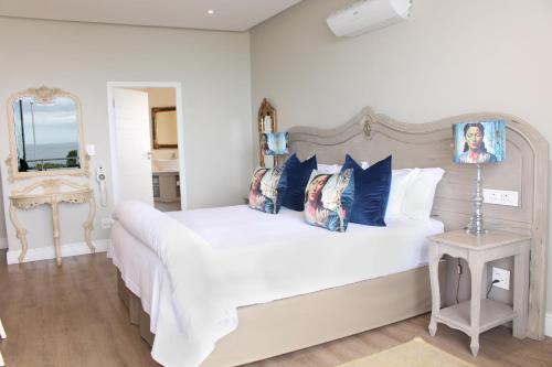 una camera da letto con un grande letto bianco con cuscini blu di Hermanus Boutique Guest House a Hermanus