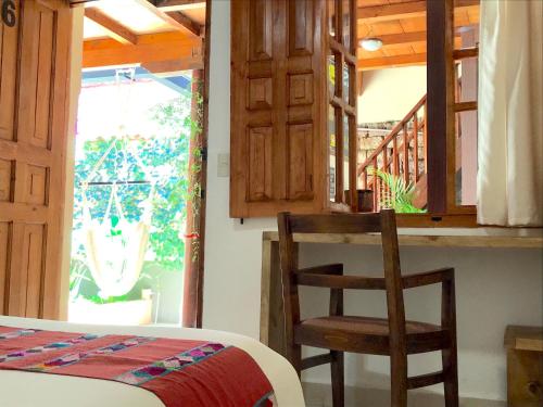 a bedroom with a bed and a chair and a window at Hotel Casa Azabache in San Cristóbal de Las Casas