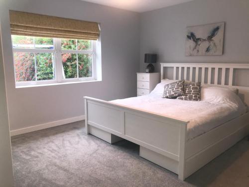 a bedroom with a white bed and two windows at Lynn Cottage St Helens Village in Saint Helens