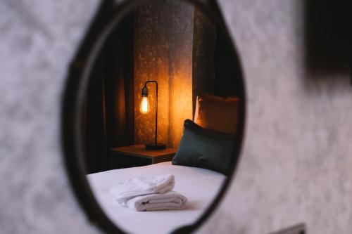 a mirror reflecting a bedroom with a bed and a lamp at The Grand Hotel in Swansea