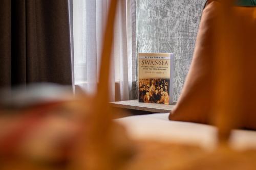 a book sitting on a table next to a window at The Grand Hotel in Swansea