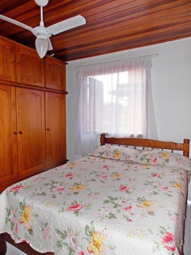 a bedroom with a bed with a floral bedspread and a ceiling fan at Casa Vila Dom Pedro in Paraty