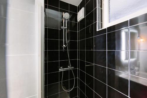 Una ducha de azulejos negros con cabezal de ducha en un baño. en L'Imperti'Nantes- T3bis de Standing, en Nantes