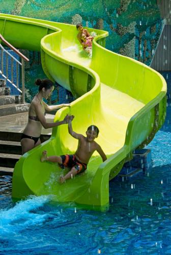 two people playing on a water slide in a pool at RIMBA by AYANA Bali in Jimbaran