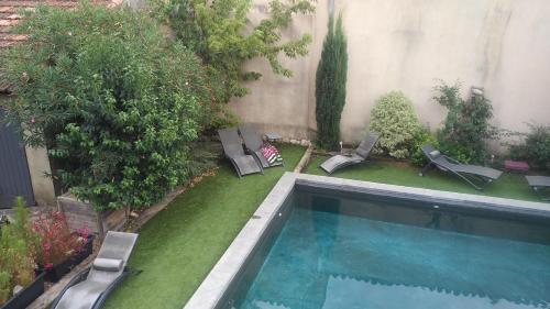 a backyard with a swimming pool with chairs and trees at Maison d'Hôtes Côté Cour in Rasteau