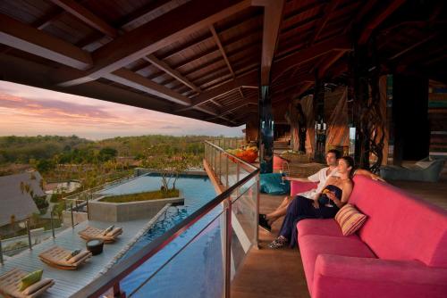 a man and a woman sitting on a couch next to a pool at RIMBA by AYANA Bali in Jimbaran