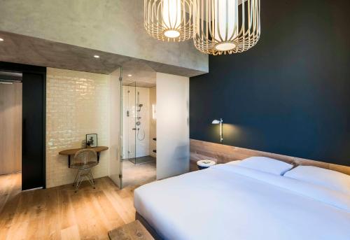 a bedroom with a large bed and two chandeliers at Hotel Arena in Amsterdam