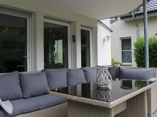 a blue couch sitting on a patio with a glass table at Ferienwohnungen am Seeufer in Möhnesee