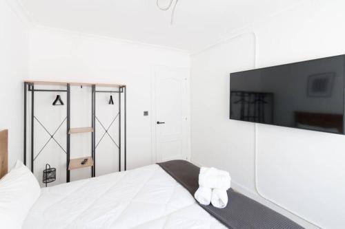 a white bedroom with a bed and a flat screen tv at Town Hall in Bilbao