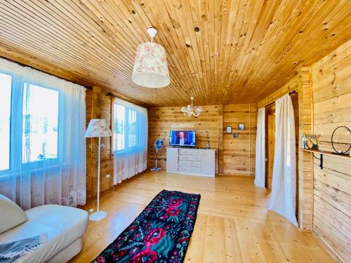 a room with a wooden ceiling with a couch and a rug at Eco house in Szack
