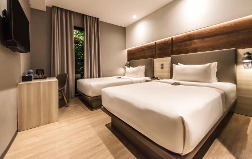 a hotel room with two beds and a television at Stanley Wahid Hasyim Jakarta in Jakarta
