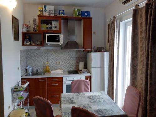 une cuisine avec une table et un réfrigérateur blanc dans l'établissement Vodice Mladen apartman za familiju, à Vodice